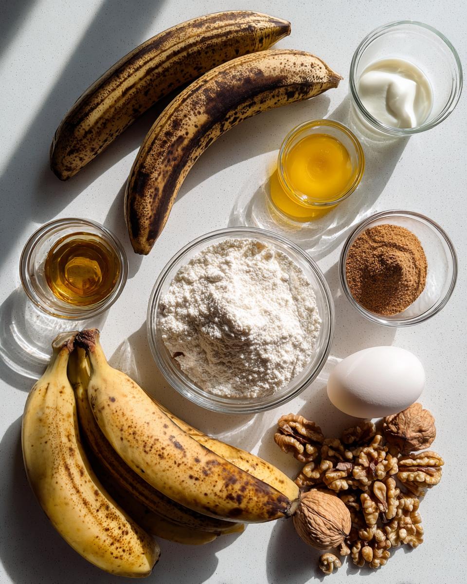 Overhead view of ingredients for banana nut muffins, including overripe bananas, flour, walnuts, egg, and spices.