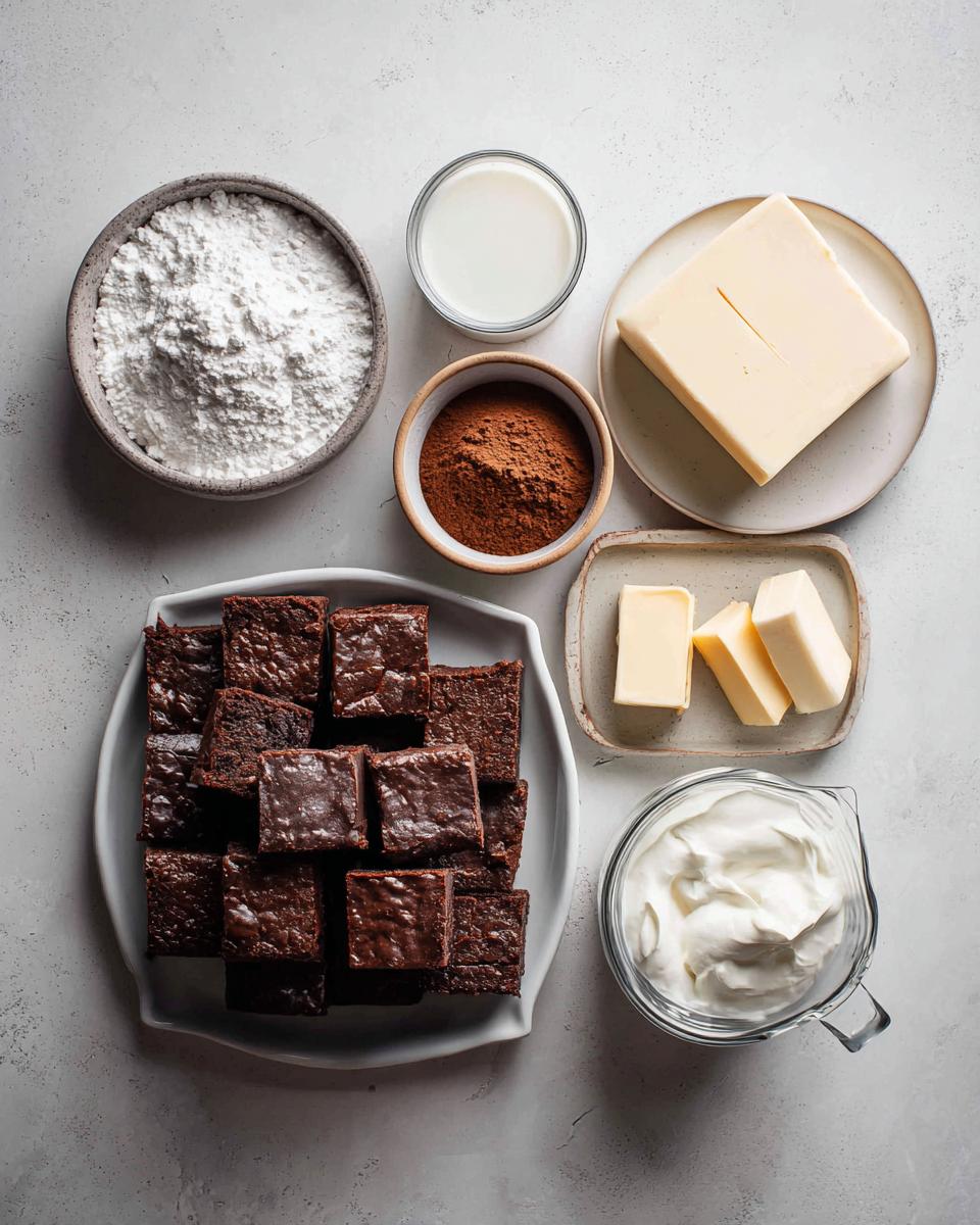 Overhead view of ingredients for brownie refrigerator cake, including cut brownies, butter, cocoa powder, powdered sugar, milk, and cream.