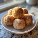 A stack of freshly made cinnamon sugar snowball cookies heavily coated in sparkling sugar crystals.