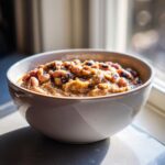 A close-up of a bowl filled with creamy, savory black eyed peas, highlighted by bright sunlight.
