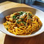 A close-up of creamy Cajun chicken pasta featuring fettuccine noodles, seasoned chicken pieces, and topped with parsley and Parmesan.