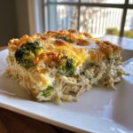 A generous serving of creamy Chicken Divan casserole featuring shredded chicken, broccoli florets, and a golden melted cheese topping.