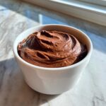 A small white bowl filled with rich, creamy chocolate dip, swirled on top.