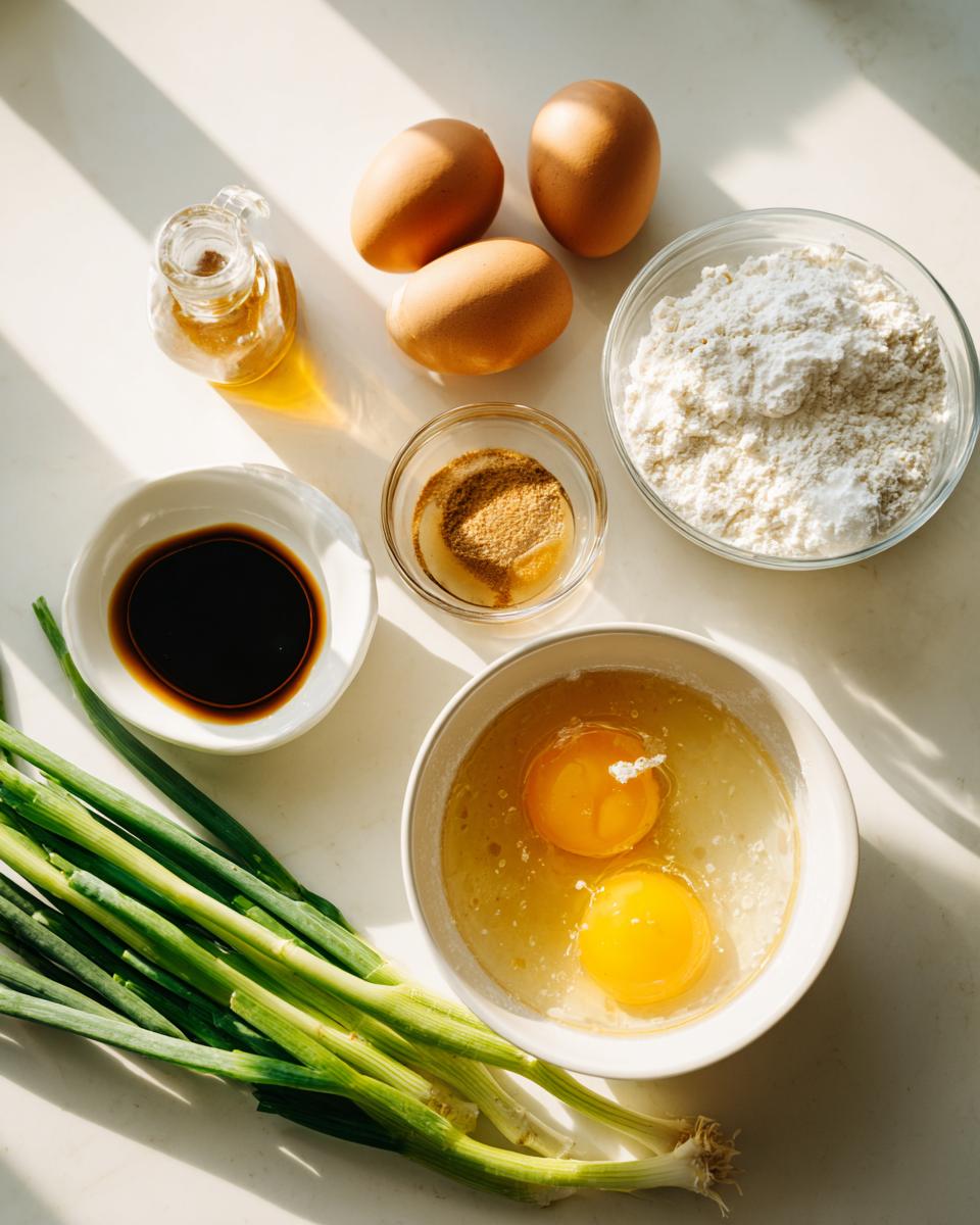 Overhead view of ingredients for egg drop soup, including cracked eggs, scallions, flour, and soy sauce.