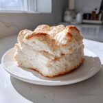 A thick, fluffy piece of homemade cloud bread with a lightly browned top, resting on a white plate.