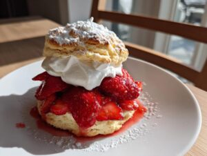 A perfect strawberry shortcake layered with macerated strawberries, whipped cream, and dusted heavily with powdered sugar.