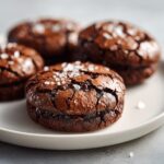 Close-up of fudgy brownie cookies topped with flaky sea salt, ready to eat.