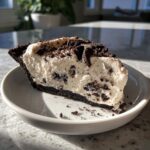 A generous slice of creamy Oreo pie with a dark chocolate crust, topped with crushed cookies.