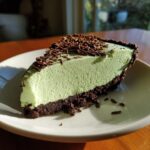 A perfect slice of light green grasshopper pie with a dark chocolate crust, topped with chocolate shavings.