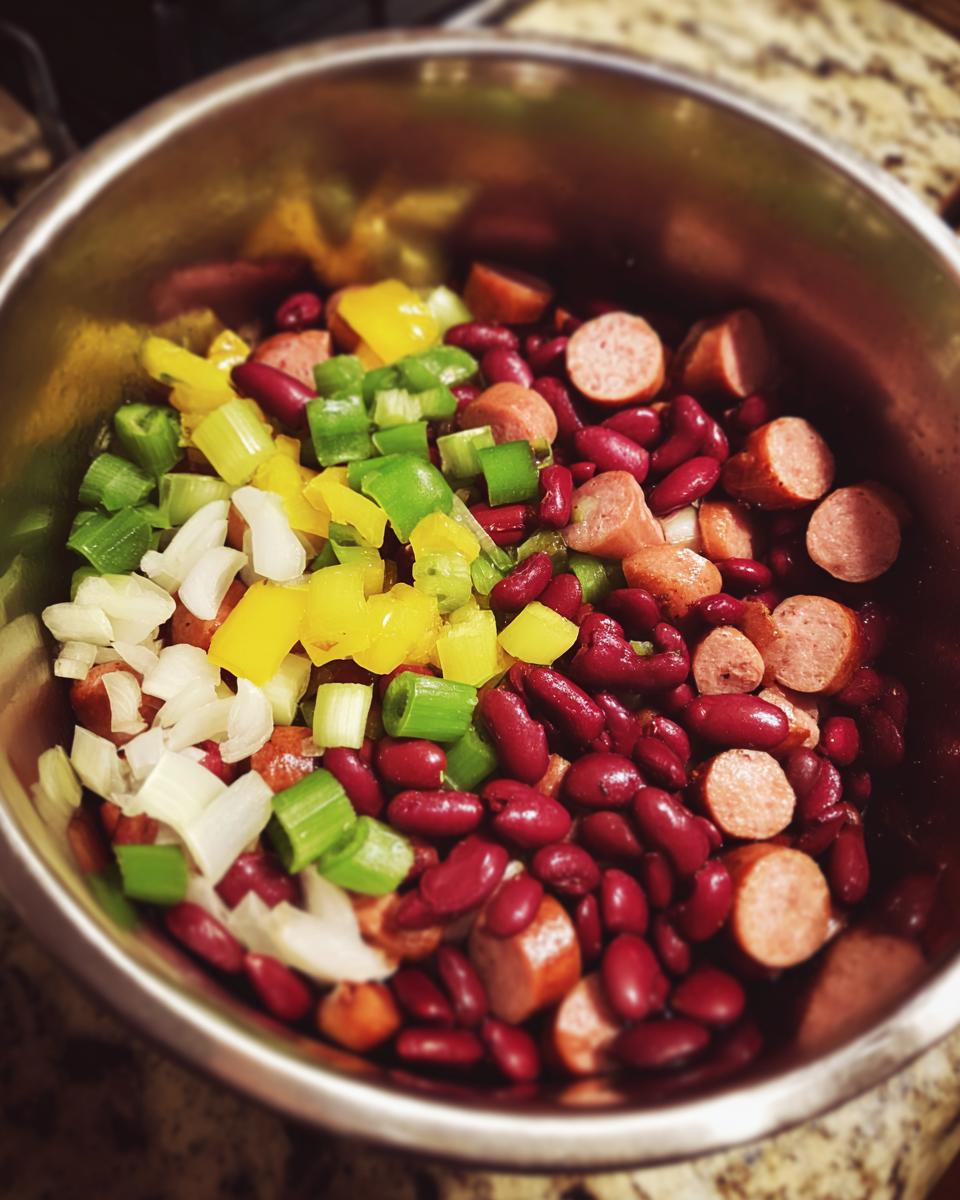 Ingredients including kidney beans, sausage slices, onions, and peppers ready for slow cooker red beans and rice.