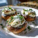 Three perfectly baked stuffed mushrooms recipe appetizers topped with creamy filling, grated cheese, and fresh parsley.
