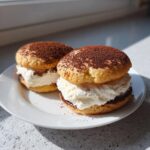 Two delicious tiramisu cookies sandwiched with thick cream filling and dusted heavily with cocoa powder.
