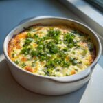 Baked jalapeno cream cheese dip topped generously with fresh chopped green onions in a white round baking dish.