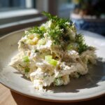 A mound of creamy cottage cheese chicken salad mixed with celery and topped generously with fresh dill.