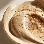 Close-up of rich, creamy swedish meatballs sauce swirled in a bowl and topped with cracked black pepper.