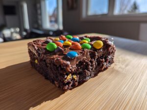 A fudgy square of cosmic brownies topped with chocolate frosting and colorful candy-coated chocolates.