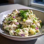 Close-up of creamy high protein cottage cheese chicken salad with chunks of chicken, red onion, and celery, topped with fresh dill.