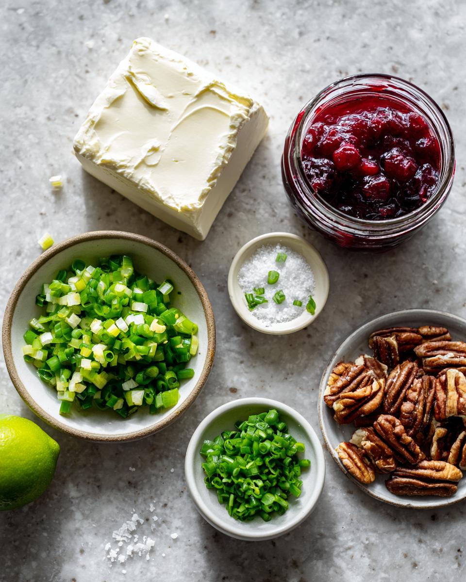 Ingredients laid out for cranberry jalapeno cream cheese dip: cream cheese, cranberry sauce, pecans, green onions, and salt.