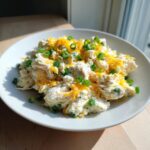 A bowl of creamy keto jalapeno popper cottage cheese chicken salad topped with shredded cheddar and green onions.
