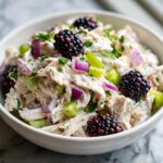 Close-up of low carb blackberry cottage cheese chicken salad with shredded chicken, blackberries, red onion, and celery.