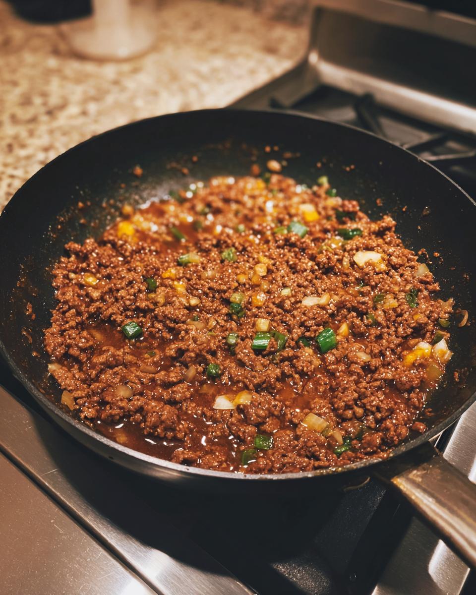 Seasoned ground beef mixture cooking in a skillet, likely the filling for high protein cheeseburger pockets.