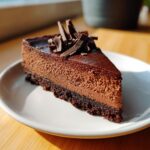 A perfect slice of no bake chocolate cheesecake with a dark chocolate crust and chocolate shavings on top.