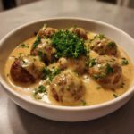 Close-up of creamy Swedish meatball recipe crockpot meatballs smothered in brown gravy and garnished with fresh parsley.