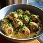 Close-up of savory Swedish meatballs covered in rich cream sauce and topped with fresh parsley.