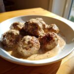 Close-up of several browned swedish meatballs with frozen meatballs smothered in a creamy, peppered gravy.