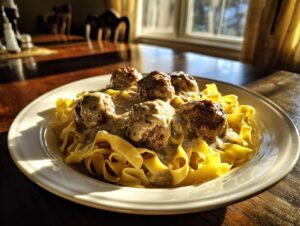 A plate of delicious swedish meatballs over egg noodles covered in creamy sauce, highlighted by sunlight.